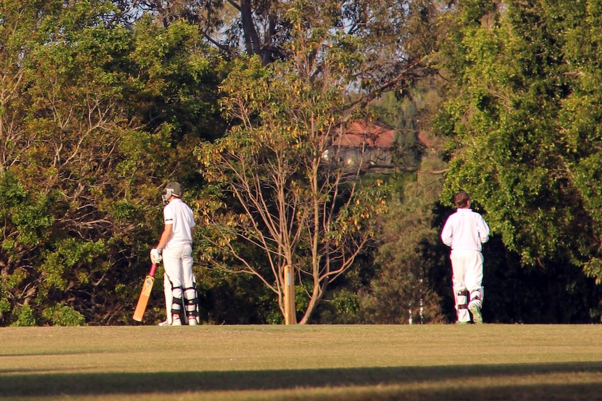 Batsman and wicketkeeper on the field during a grade cricket match.