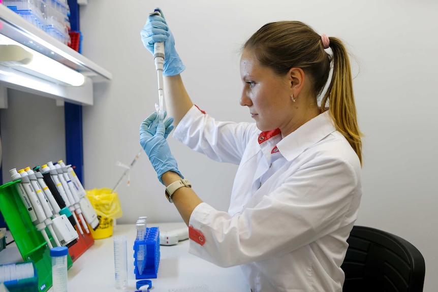 A woman looks at a test tube at a lab in Moscow, Russia.