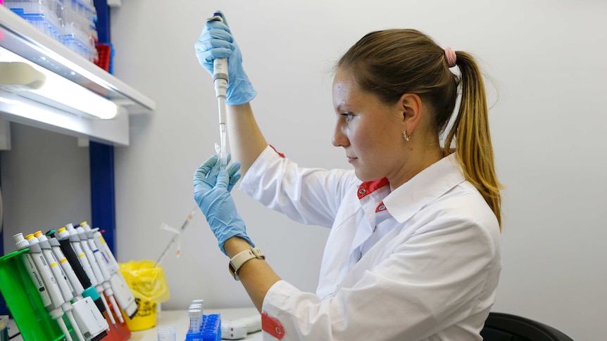 A woman looks at a test tube at a lab in Moscow, Russia.