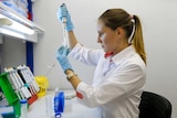 A woman looks at a test tube at a lab.