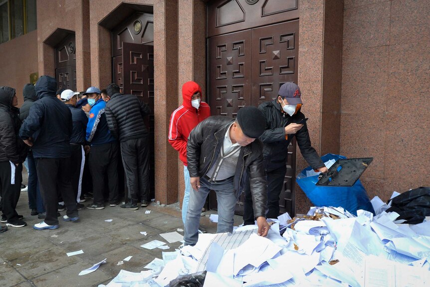 Protesters look through papers ransacked from a government office
