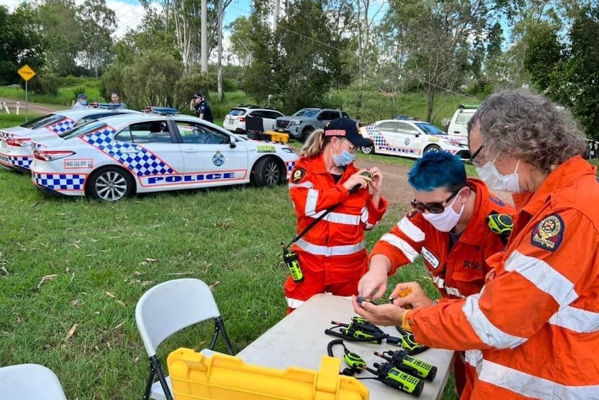 Queensland Police and SES personnel stand in a field in search for missing police dog PD Quizz 