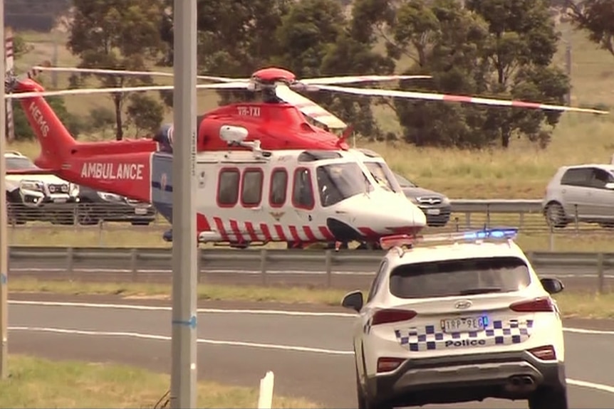 An air ambulance helicopter lands in front of a police vehicle.