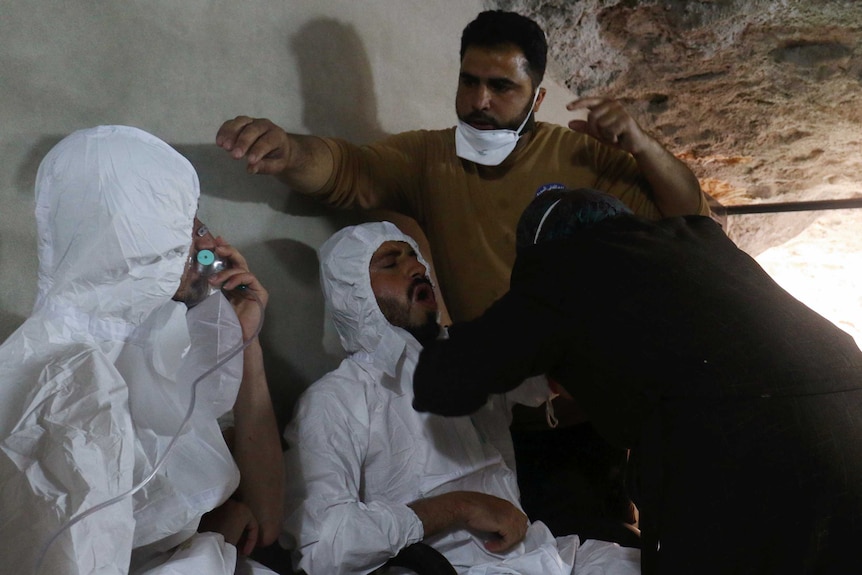 A man breathes through an oxygen mask as another one receives treatments after a suspected gas attack in Syria.