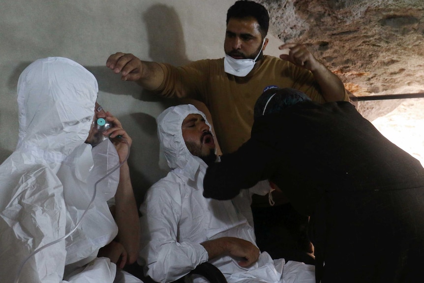 A man attended by rescue workers breathes through an oxygen mask