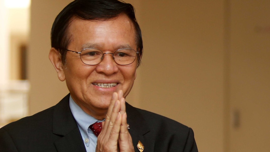 A close-up photo of Kem Sokha holding his hands up to his face.