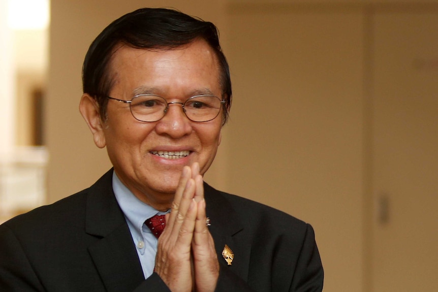 A close-up photo of Kem Sokha holding his hands up to his face.