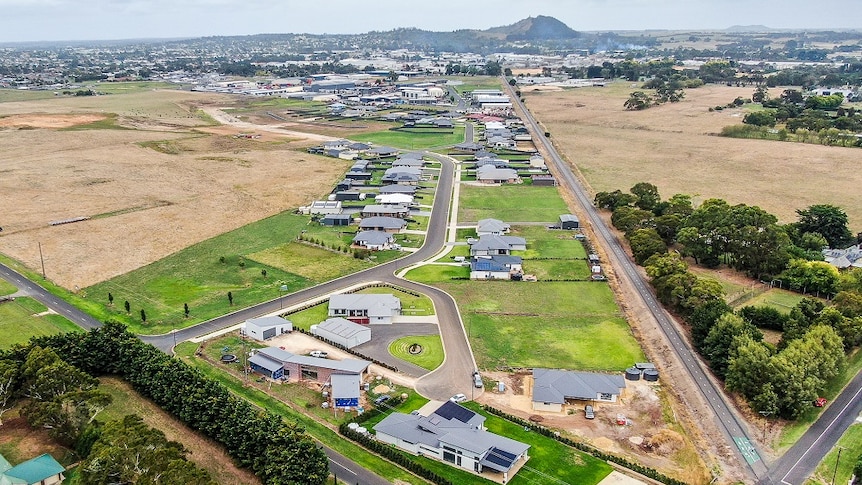 An aerial view of roads, houses and hedges, with a volcano in the background