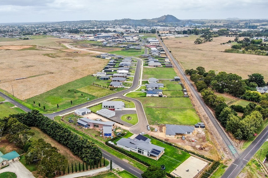 An aerial view of roads, houses and hedges, with a volcano in the background