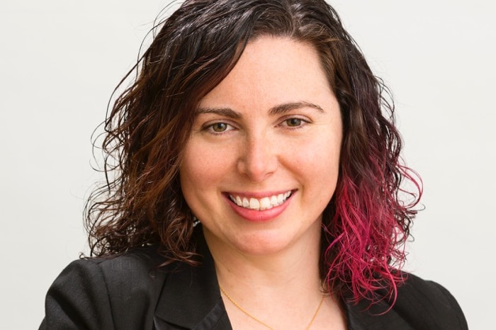 Head and shoulders image of a smiling woman in a suit jacket.