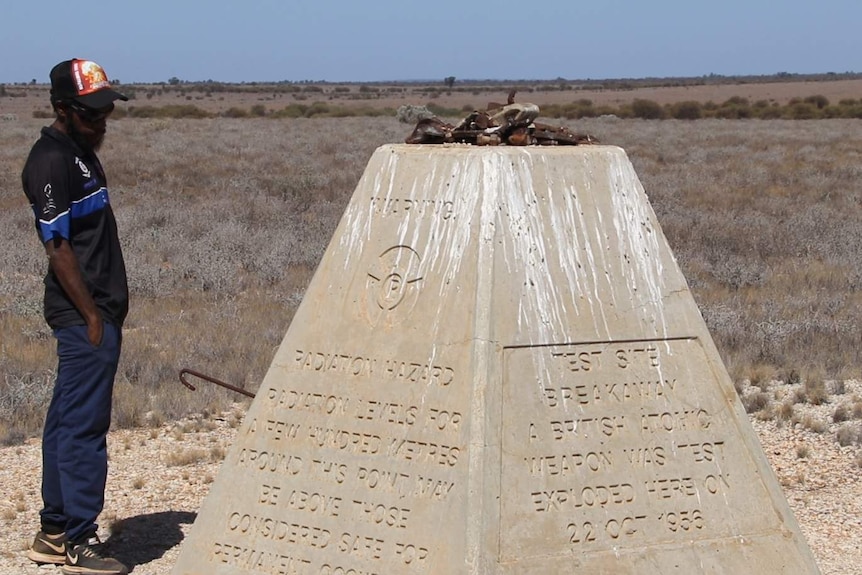 An Anangu man stands looking at a monument to the testing at Maralinga.