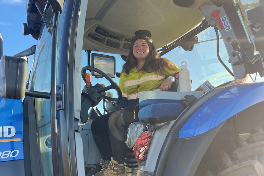 A woman sitting inside a tractor wearing a high-vis top