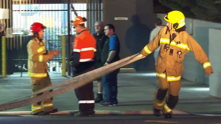 fireman dragging a hose across a street