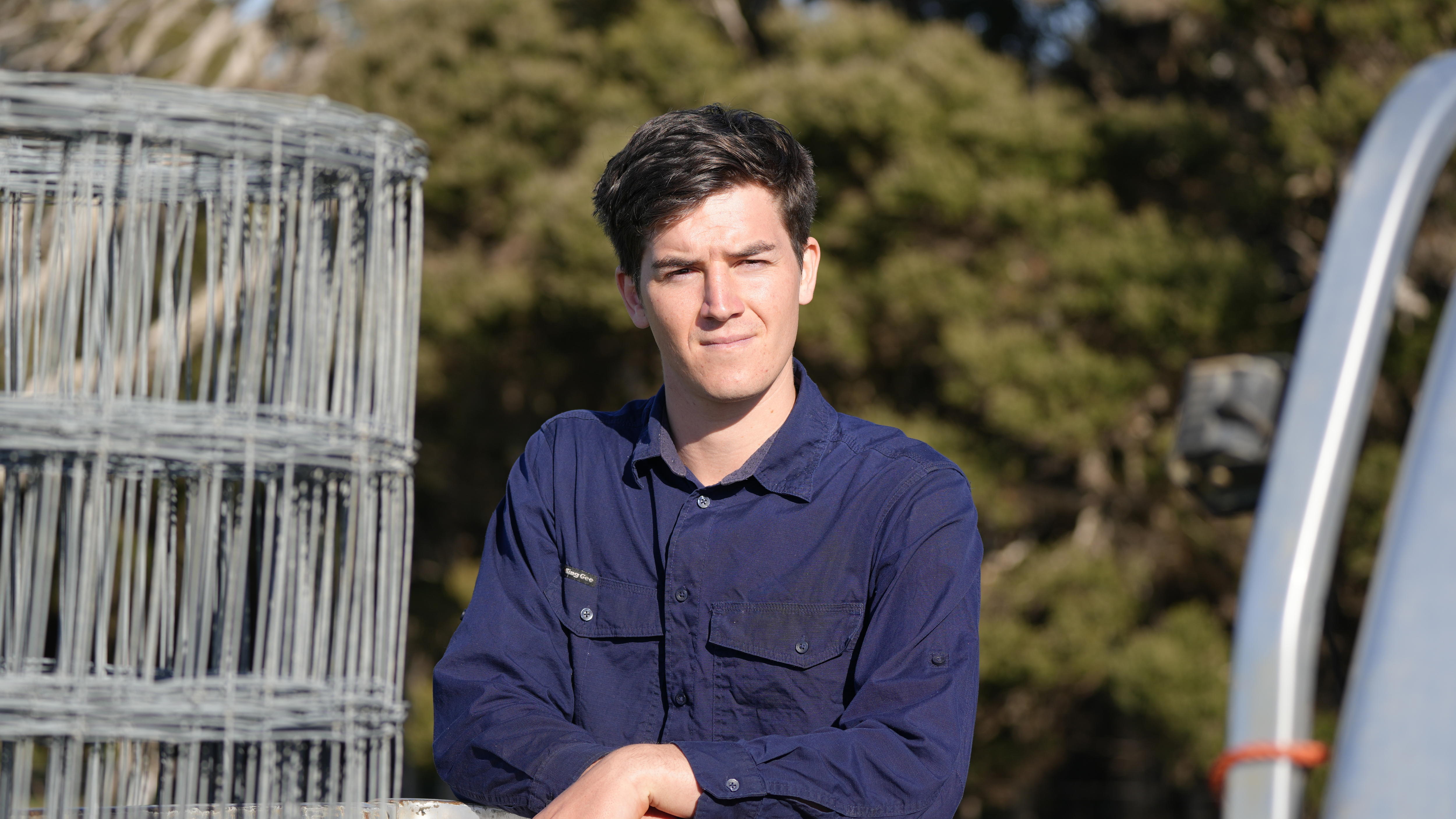 a man in a blue shirt looks serious into the distance.