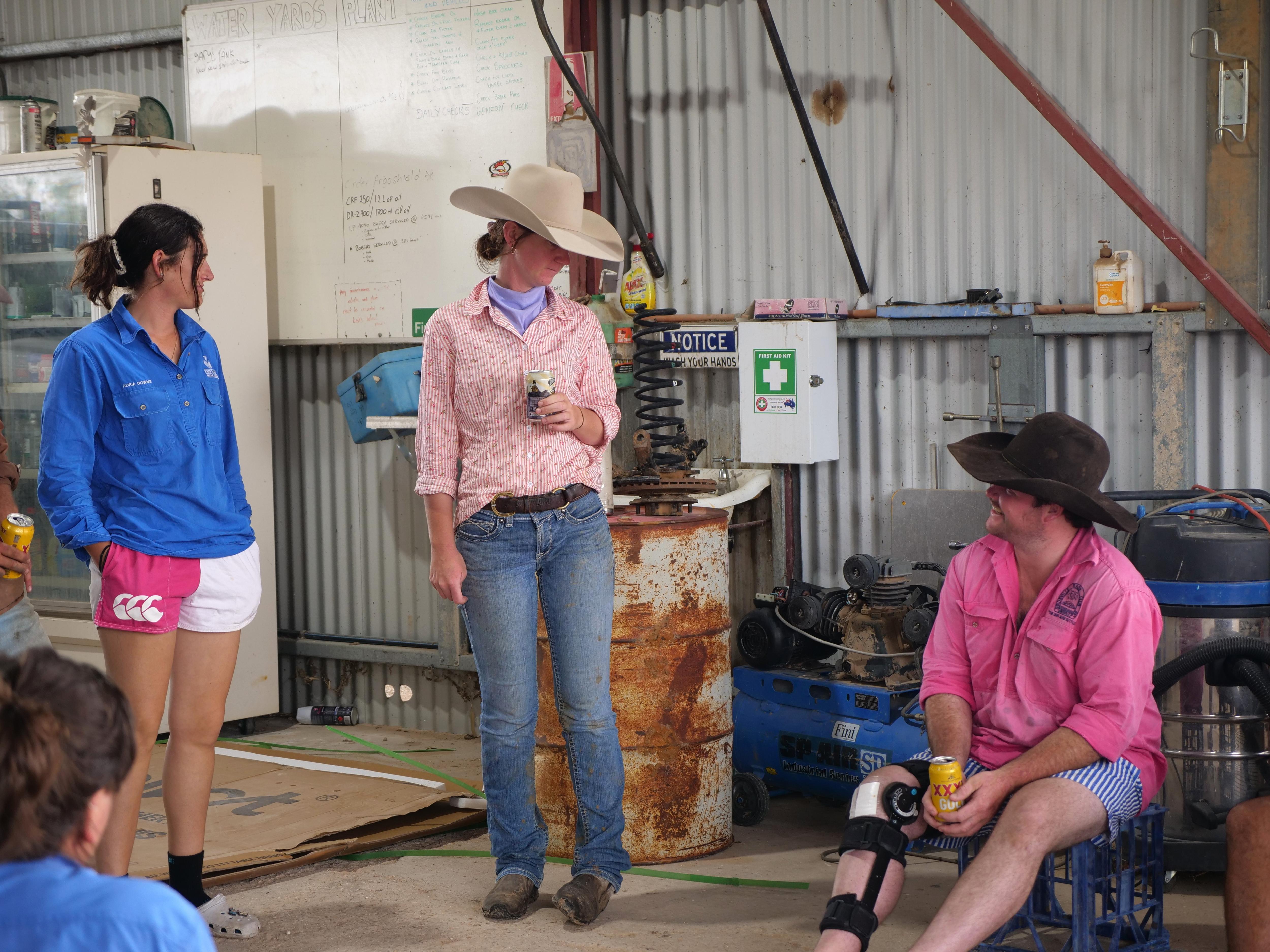 Três trabalhadores parados em um galpão conversando enquanto tomavam uma cerveja. 