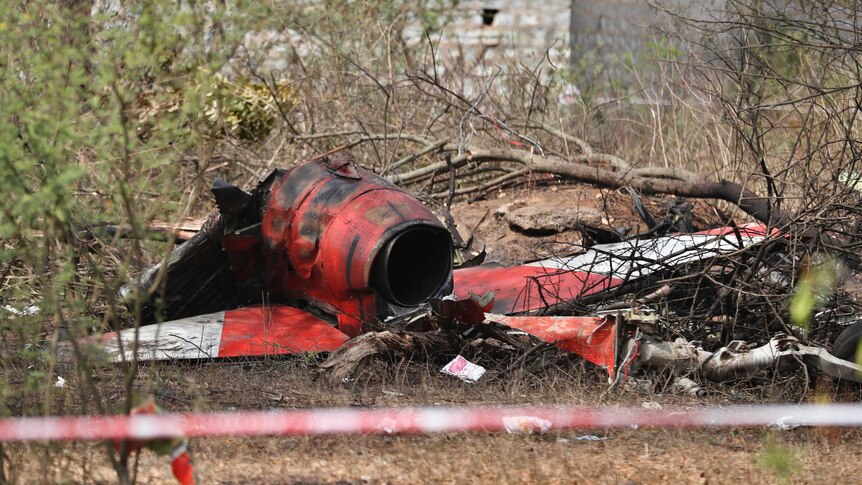 Red debris from plane lies on the ground.