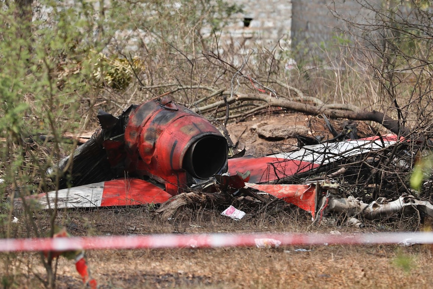 Red debris from plane lies on the ground.