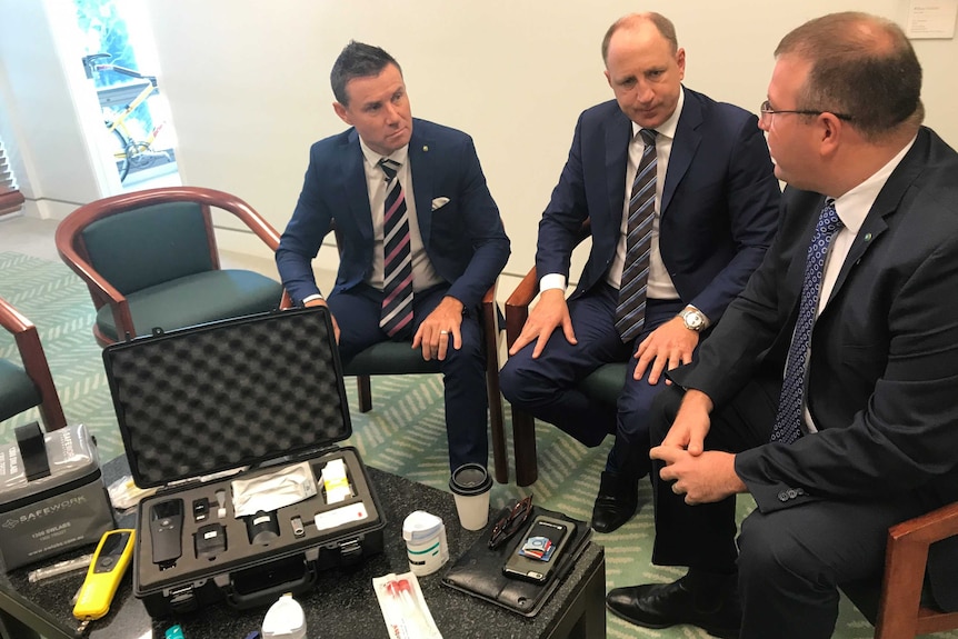 Andrew Laming (l), Luke Howarth (c) and Ben Morton (r) sit by a low table with a drug testing kit on it