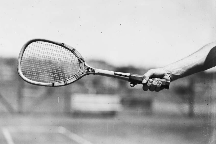 A black and white photo of a man holding a tennis racquet