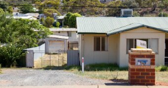 An empty home with a sale sign out front.