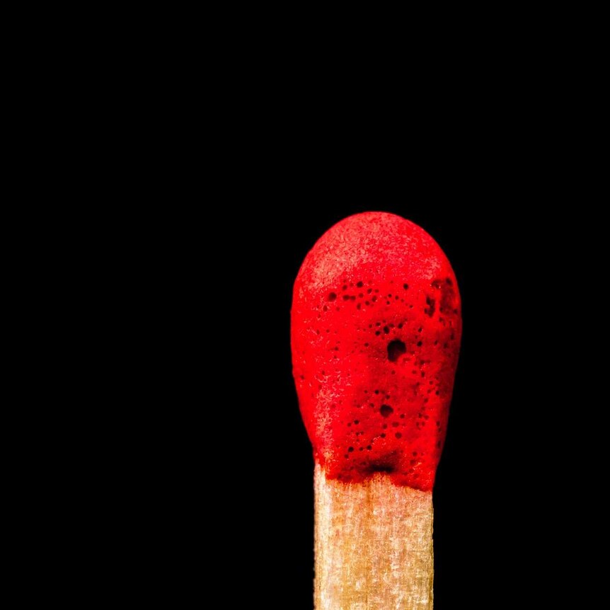 A close up of a red tipped match with a black background