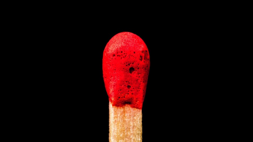 A close up of a red tipped match with a black background