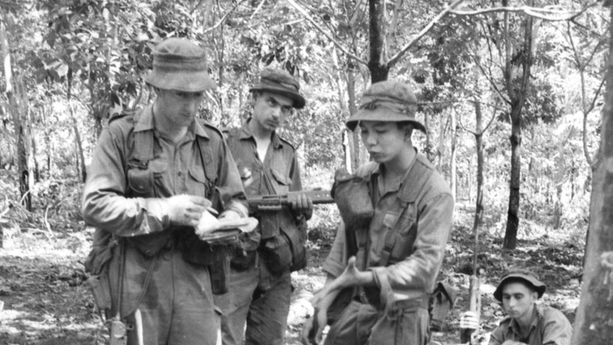 Captain Bryan Wickens questions a wounded Viet Cong prisoner at Long Tan with the help of a Vietnamese interpreter.