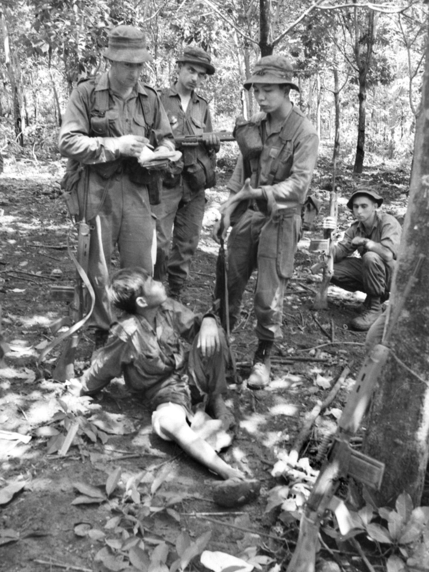 Captain Bryan Wickens questions a wounded Viet Cong prisoner at Long Tan with the help of a Vietnamese interpreter.