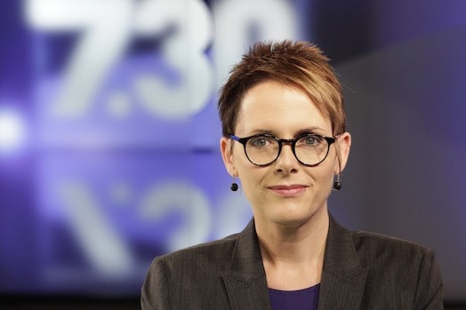 Lane standing in front of 7.30 logo in studio.