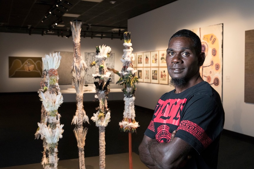 Matthew Dhamuliya Gurruwiwi stands with his art work