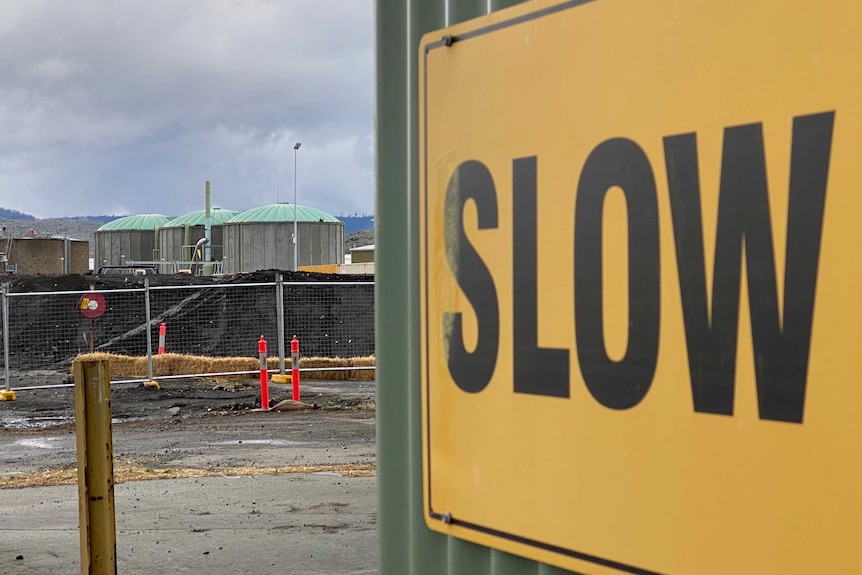 A sign saying slow next to a sewage treatment plant