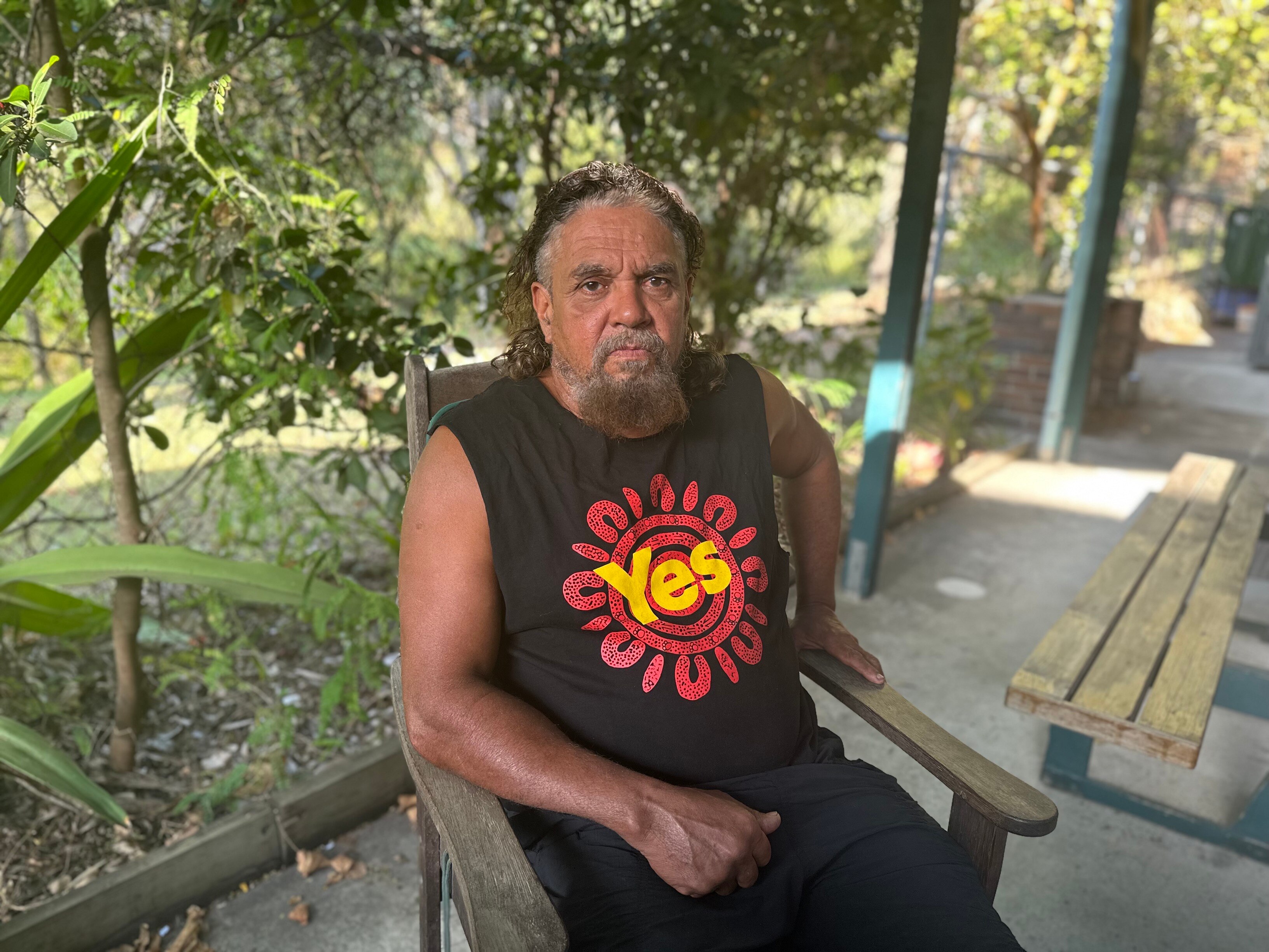 Darren sits in a chair in his Yes shirt 