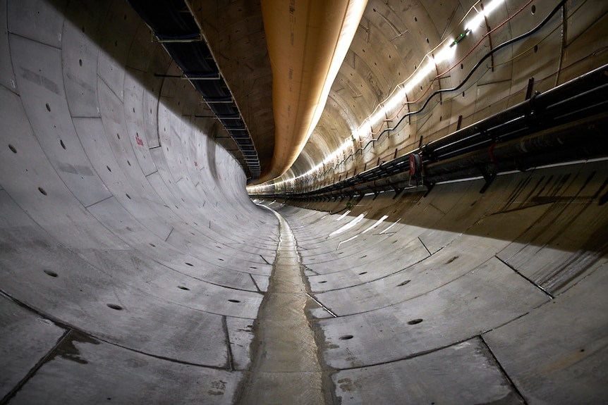 A long, gently curving round tunnel lined with concrete.