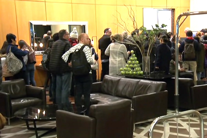 A crowd queues in a foyer.