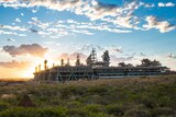 Gas plant infrastructure on a scrubby island at sunrise.