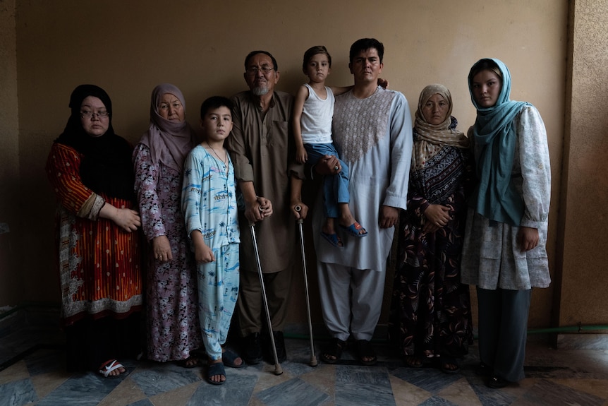 A group of eight people across at least three generations stand together. 