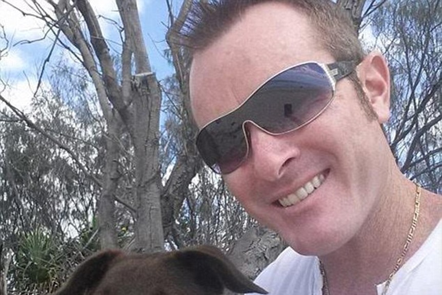 Dan Shearin smiles in a photo wearing sunglasses, holding a dog.