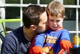 Leigh Chivers hugs his son Hugh, who is wearing a Superman costume.
