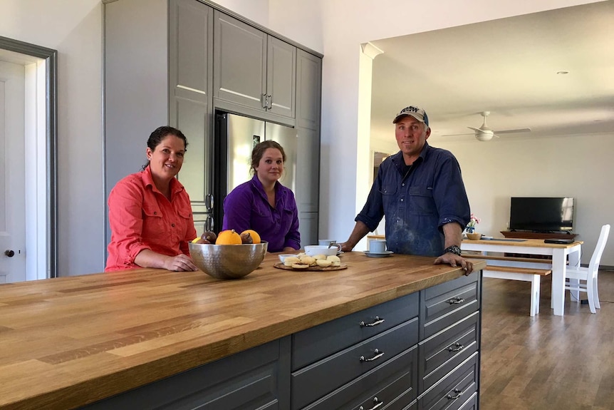A trio stand in a renovated kitchen