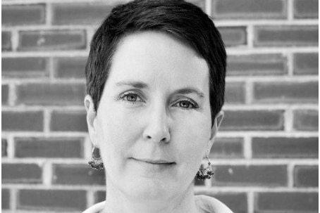 A woman standing against a brick wall