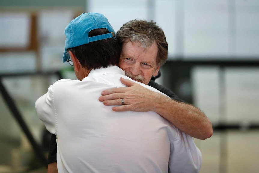 Baker Jack Phillips, owner of Masterpiece Cakeshop, left, is hugged by a man