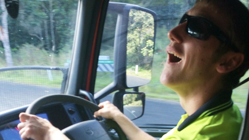 A man smiling behind the wheel of a truck.