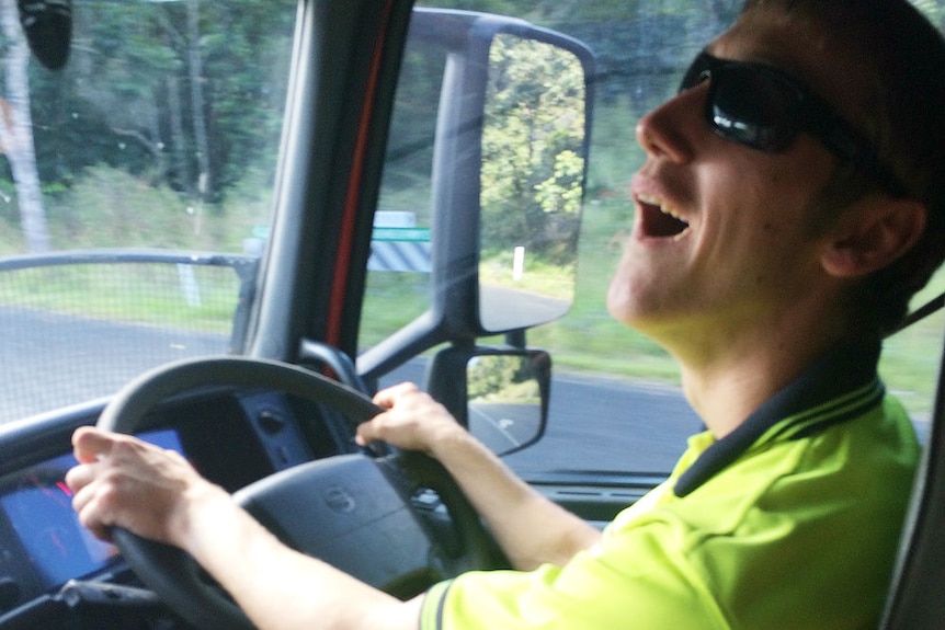 A man smiling behind the wheel of a truck.