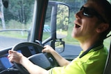 A man smiling behind the wheel of a truck