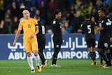 Aaron Mooy looks dejected with his eyes closed, with Thailand players in the background.