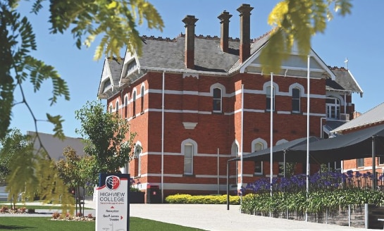 A red-brick three-storey building with a garden in front.