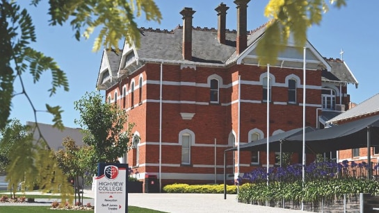 A red-brick three-storey building with a garden in front.