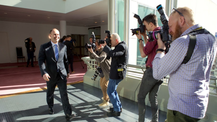 Josh Frydenberg is greeted by a pack of photographers.