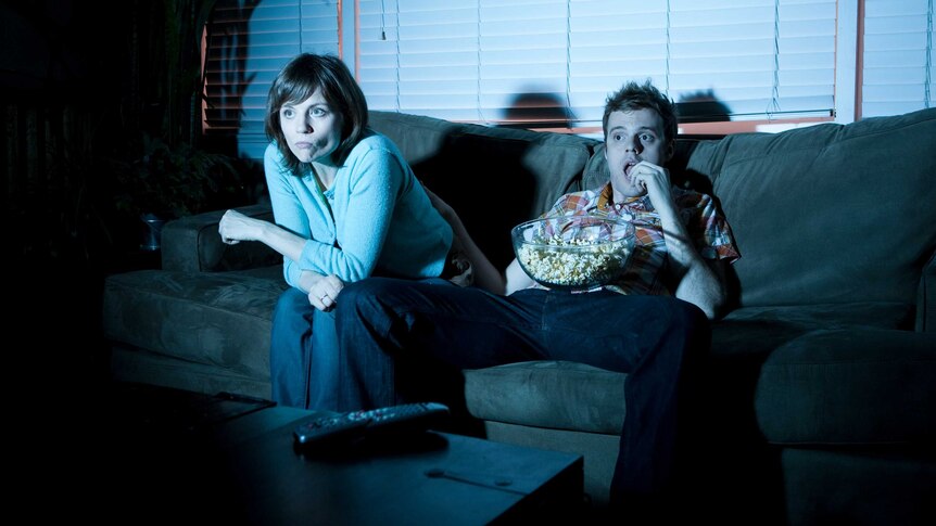 Man and woman on couch watching television