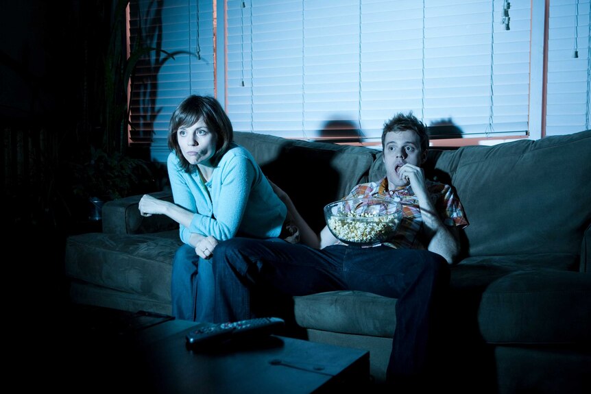 Man and woman on couch watching television